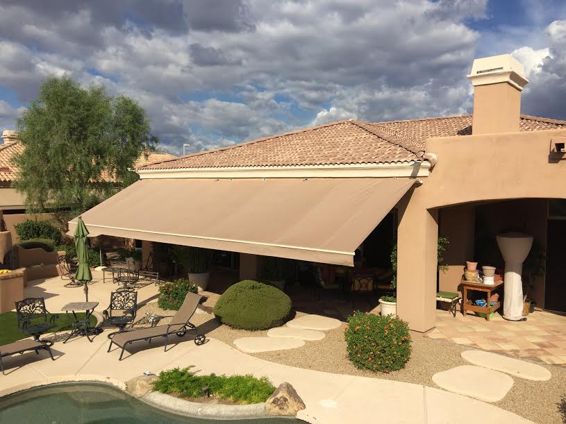 A pool-side patio with a retractable awning providing shade on a sunny day.