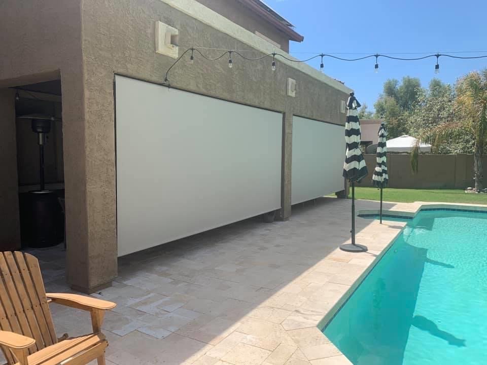 A pool-side patio area covered with rolled down patio shades on a sunny day.