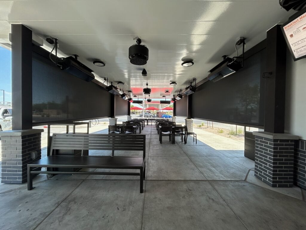 Motorized Shades Installed Along a Covered Walkway to Reduce Sun Glare and Improve Outdoor Seating Comfort